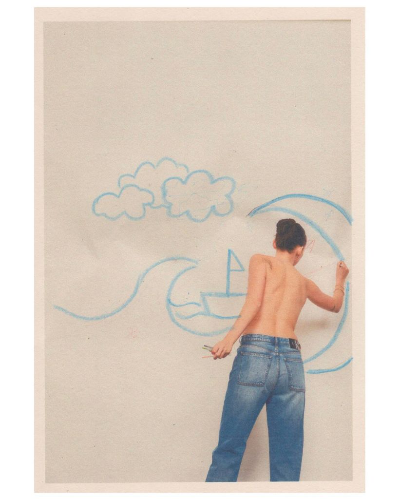 Femme en jeans dessinant un bateau sur un mur