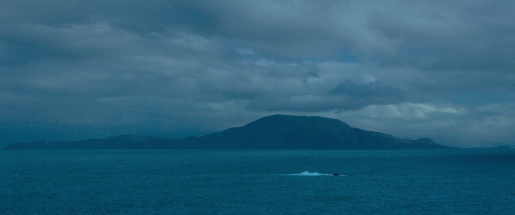 Sous un ciel brumeux, une île se distingue au loin.